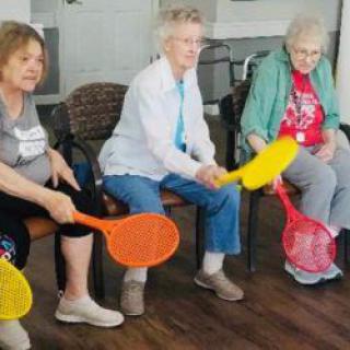 A group of seniors enjoying an indoor activity with colorful paddles.