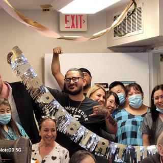 A group of people celebrating indoors with decorations and wearing masks.
