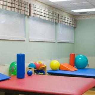 A therapy room equipped with colorful exercise mats and various fitness balls for rehabilitation.