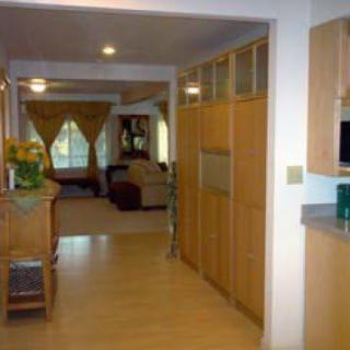A view from the kitchen into a hallway leading to the living room, featuring wooden cabinetry and modern decor.