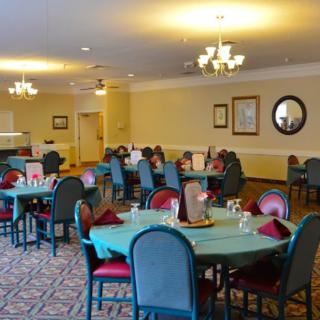 A spacious dining room with neatly arranged tables and chairs, illuminated by elegant chandeliers.