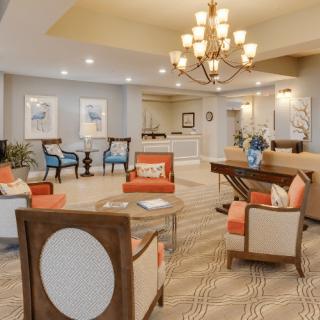 A warmly decorated living room with comfortable seating and a central chandelier.