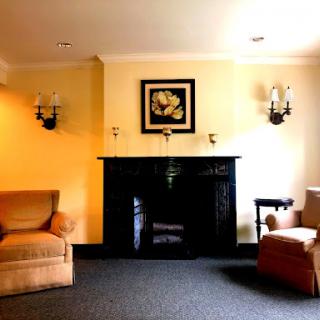 A cozy living room featuring two armchairs, a fireplace, and warm wall colors.