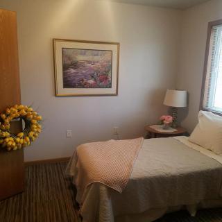 A cozy bedroom with a single bed, decorated with a lamp and a painting on the wall.