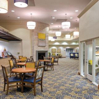 A modern dining area with tables and chairs, featuring stylish lighting and carpeted flooring.
