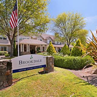 Front view of a building with a sign and landscaped gardens.