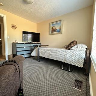 A cozy bedroom featuring a bed, a dresser, and a television.
