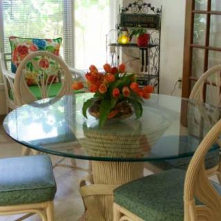 A bright dining room with a glass table adorned with orange tulips, surrounded by chairs featuring floral patterns.