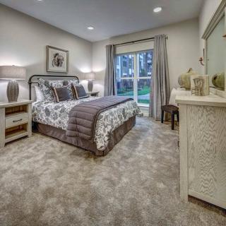 A well-decorated bedroom with a double bed, lamps, and a large window offering natural light.