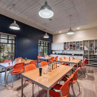 A modern kitchen and dining area with orange chairs and industrial lighting.