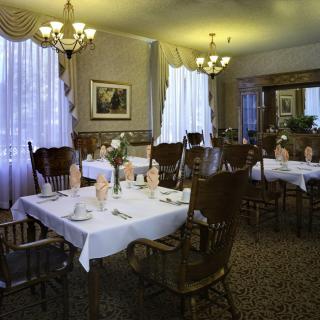 A cozy dining room with elegantly set tables and warm lighting.