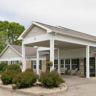 A front view of a building entrance with a covered porch and landscaped surroundings.