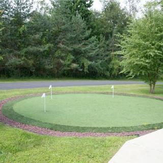 A small outdoor putting green surrounded by lush greenery and trees.
