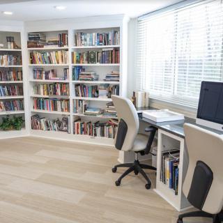 A bright and organized home office with bookshelves, a desk, and a computer setup by the window.