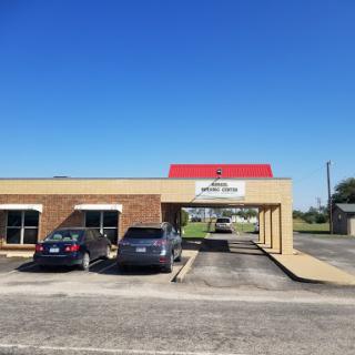 A view of a commercial building with a red roof and parked cars under a clear blue sky.