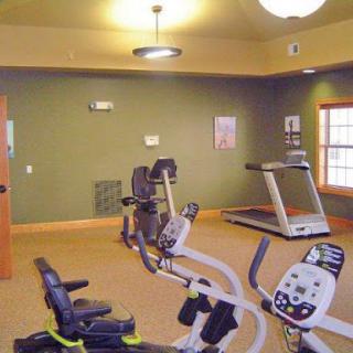 A well-equipped gym featuring a treadmill and stationary bikes, designed for indoor workouts.