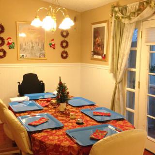 A cozy dining room with a festive table setting, featuring holiday-themed decorations and a small Christmas tree centerpiece.