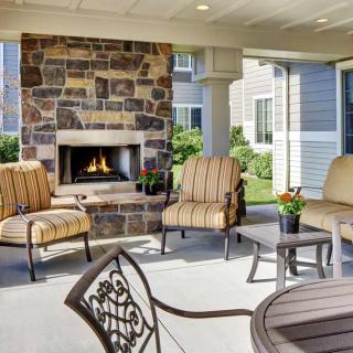 A cozy outdoor patio with a stone fireplace and comfortable seating.