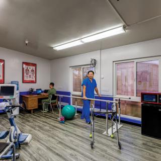 A physical therapy room equipped for patient rehabilitation, featuring exercise equipment and healthcare professionals.