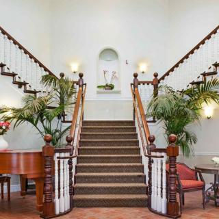 A grand staircase with elegant decor and a piano in the entrance hall.