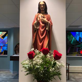 A serene interior display featuring a statue and fresh roses.