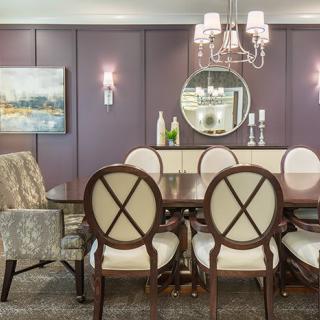 A beautifully decorated dining room featuring elegant chairs and a wooden table, complete with a chandelier and wall-mounted mirror.