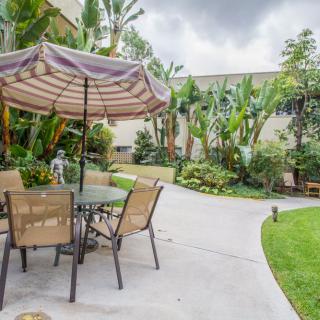 A tranquil backyard patio with seating area and lush greenery.