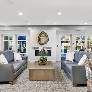 A modern living room with sleek sofas, a central coffee table, and a decorative fireplace.