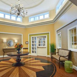 Elegant lobby with a chandelier and intricate wood flooring design.