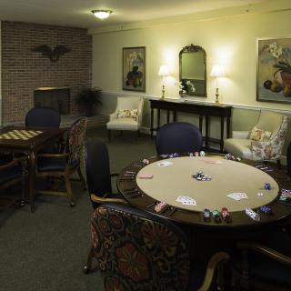 A cozy game room featuring a poker table with chairs and warm lighting.