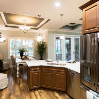 A modern kitchen and dining area featuring wooden cabinets, stainless steel appliances, and elegant lighting.