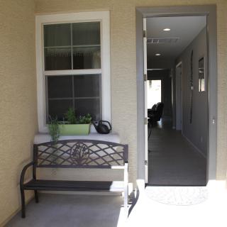 A bench and potted plant are positioned outside a doorway leading to a well-lit hallway.