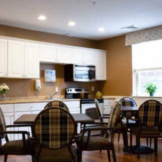 A cozy kitchen and dining area featuring a table with chairs, white cabinets, and a microwave.
