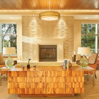 A modern living room with a central fireplace and wooden furniture, featuring neutral tones and elegant lighting.
