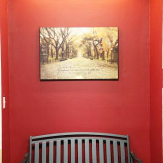 A cozy interior space featuring a red wall and a serene painting above a wooden bench.