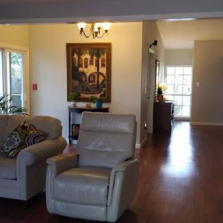 A cozy living room with modern furniture, including a sofa and armchair, adorned with artwork and a hardwood floor.