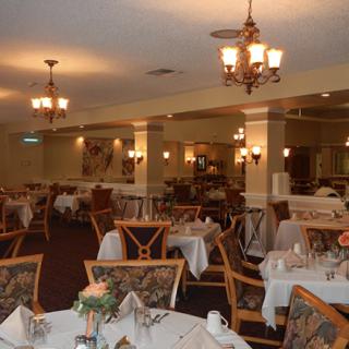 An elegant restaurant dining room with neatly arranged tables and chandeliers.