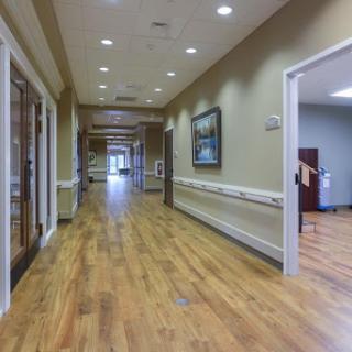 A well-lit hallway featuring wooden flooring and decorative artwork on the walls.