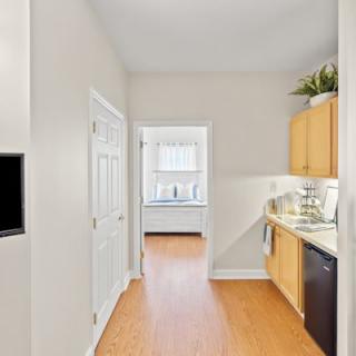 A bright, modern apartment kitchen with wooden floors and light-colored cabinets.