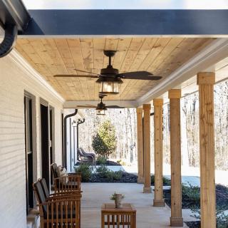 A cozy covered porch with wooden furniture and ceiling fans.