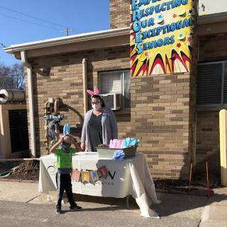 A lively outdoor booth set up for a community event, featuring a child and an adult ready to engage visitors.