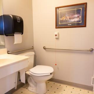 A clean bathroom with a toilet, sink, and safety grab bars.