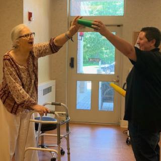 A joyful interaction between an elderly individual and a caregiver, engaging in a playful activity indoors.