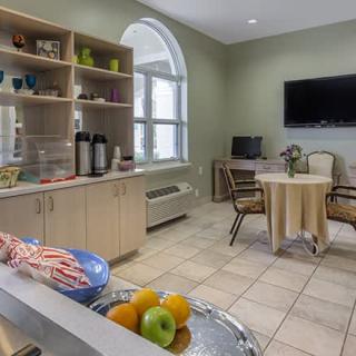 A cozy kitchen and dining area with a TV, table and chairs, and a display of fruit.