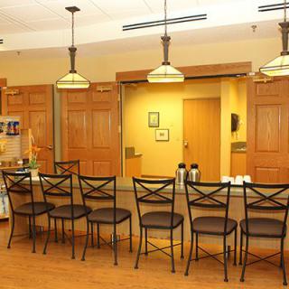 A warm, inviting kitchen area with a bar counter and stools, complemented by hanging lights and wooden cabinets.