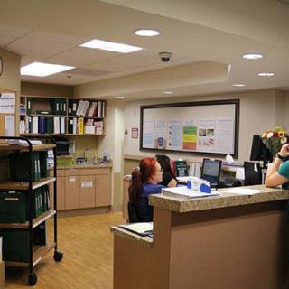 A hospital reception area with staff working at computers behind a desk.
