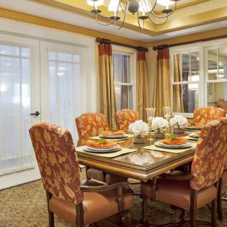 A beautifully decorated dining room with a set table and upholstered chairs.