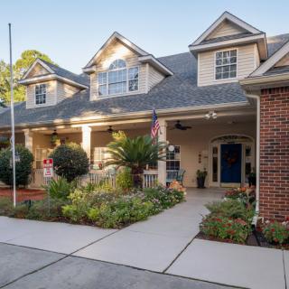 A two-story residential house with a large porch and landscaped front yard.