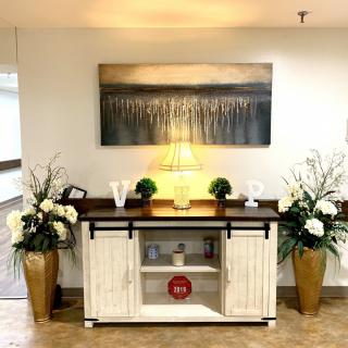 A well-decorated console table with a lamp, artwork above, and plants on either side.