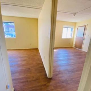Empty apartment interior with wood flooring and natural light.